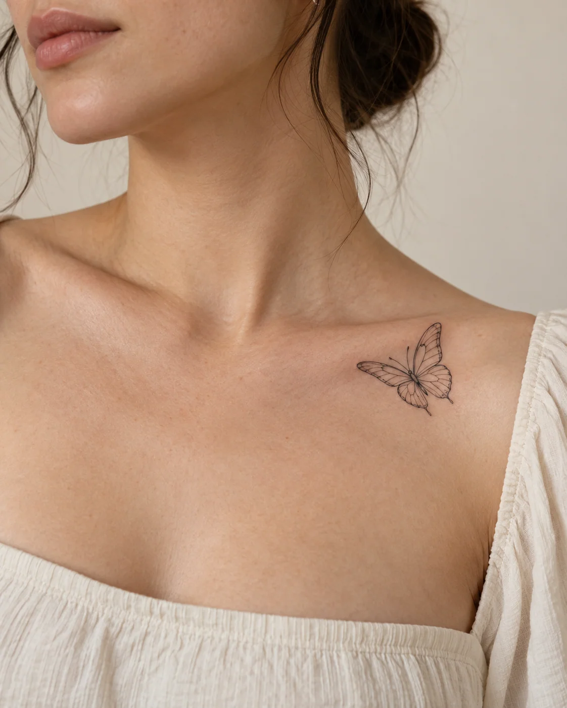Butterfly Above the Collarbone fine line tattoo concept on the collarbone below a visible neckline