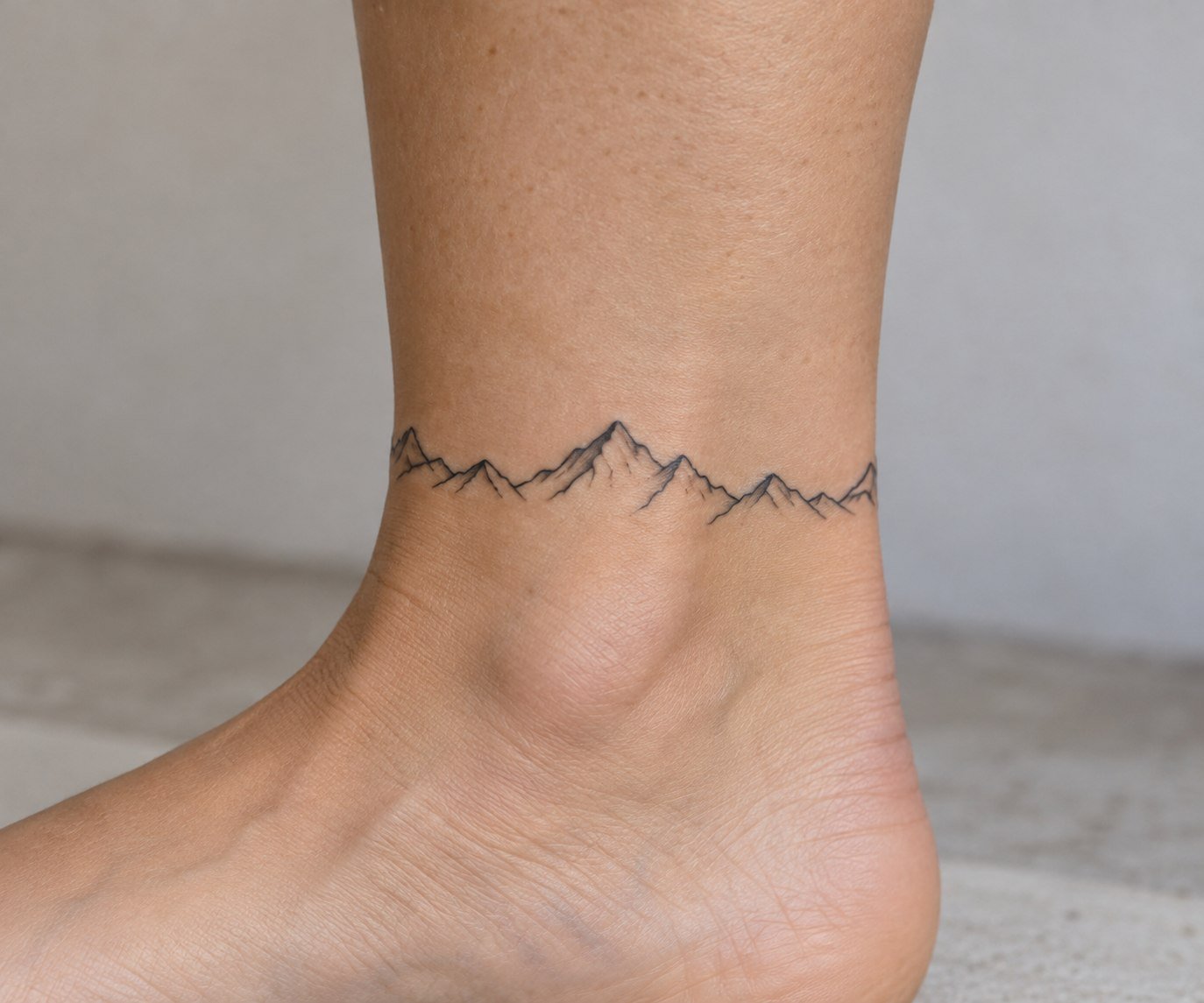 Minimal mountain horizon tattoo in fine-line black ink.