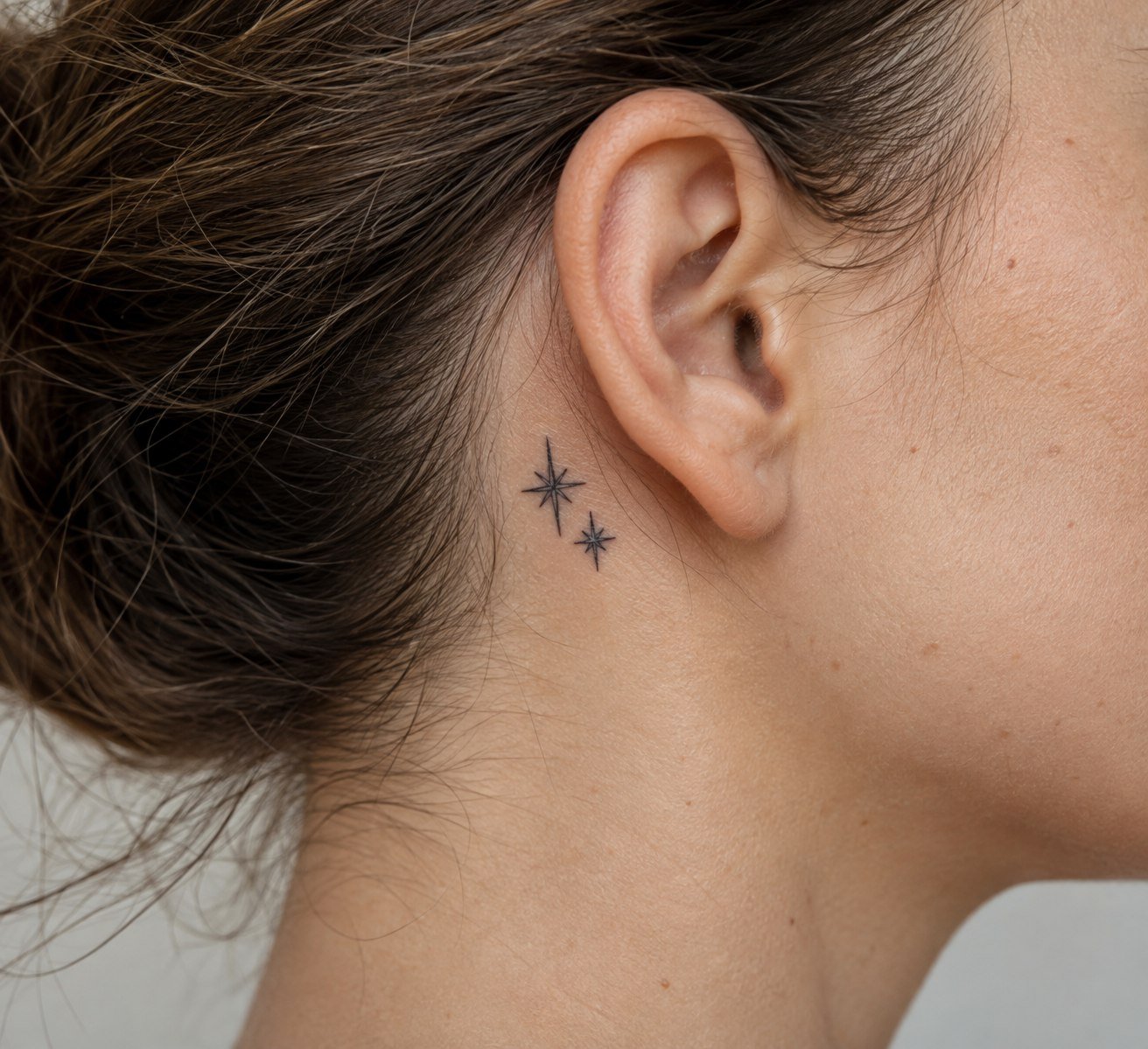 Two small star tattoos behind the ear.