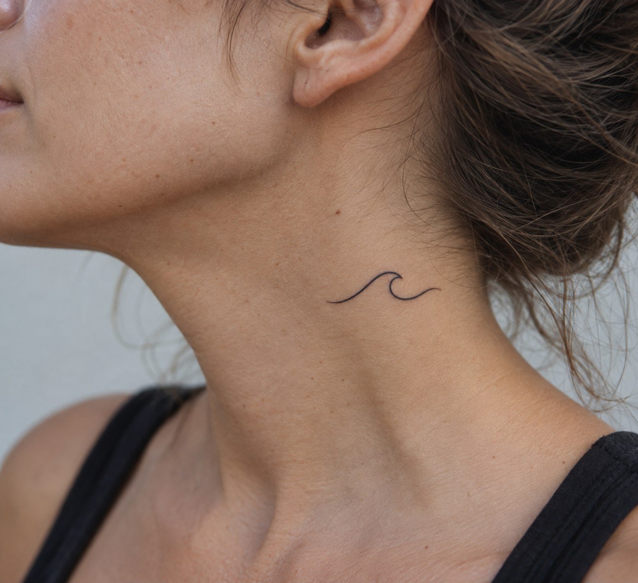 Small fine-line wave tattoo on the side of the neck.