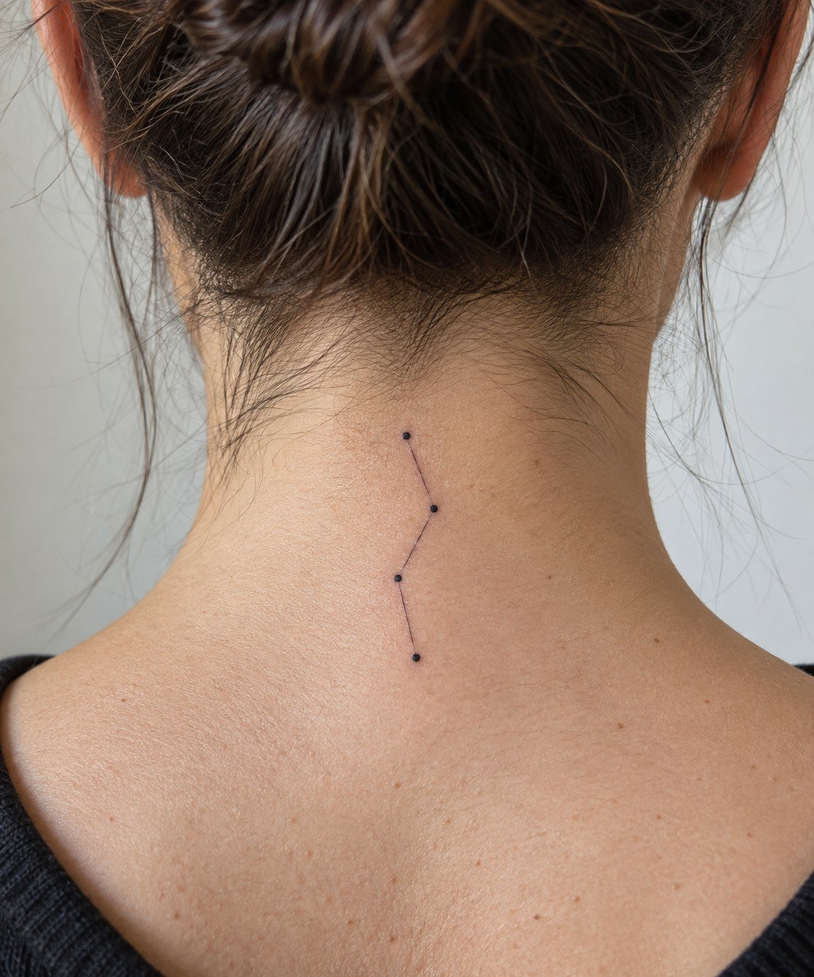 Small vertical constellation tattoo at the nape.