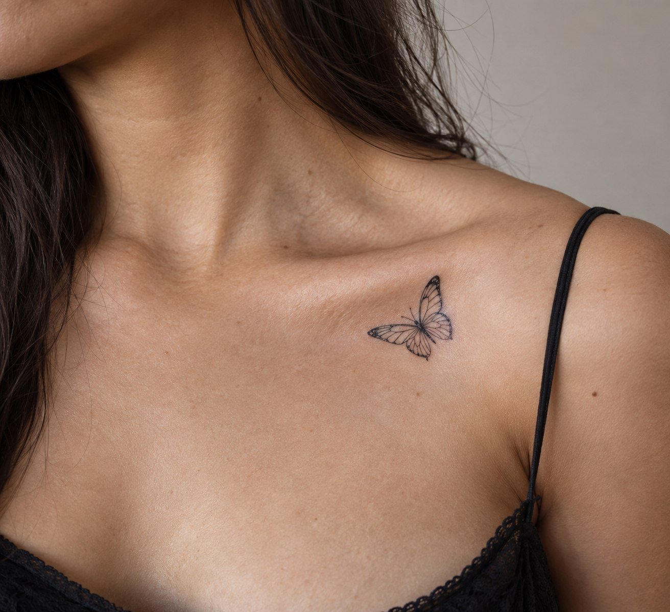 Delicate butterfly tattoo placed along the collarbone.