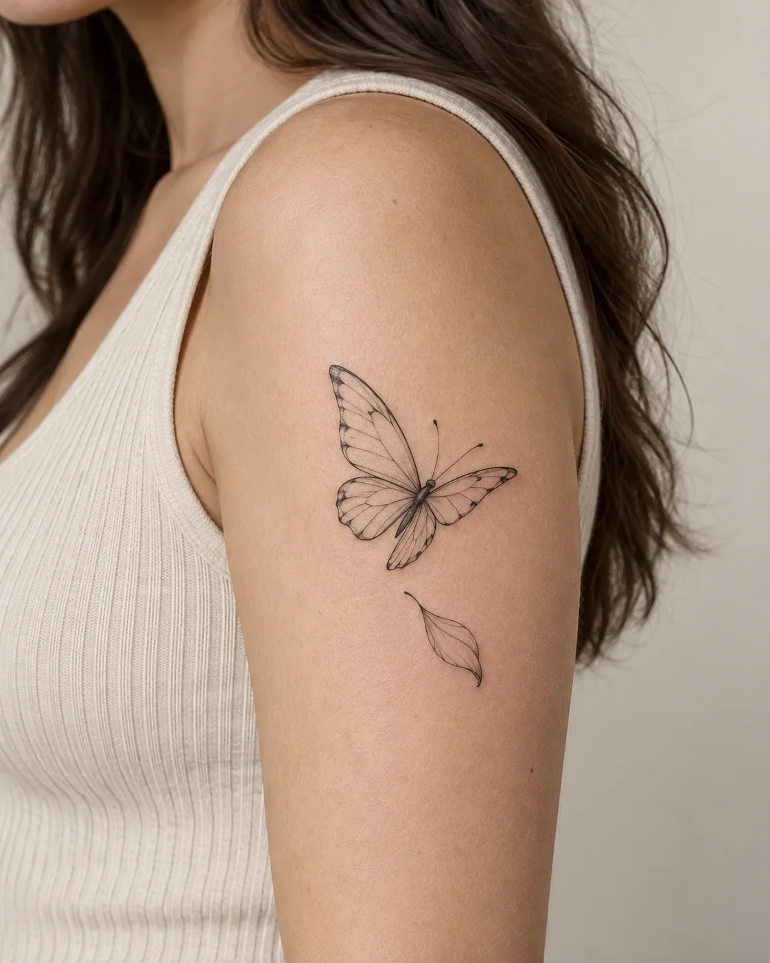 Butterfly with a Single Falling Petal fine line tattoo concept on the outer upper arm