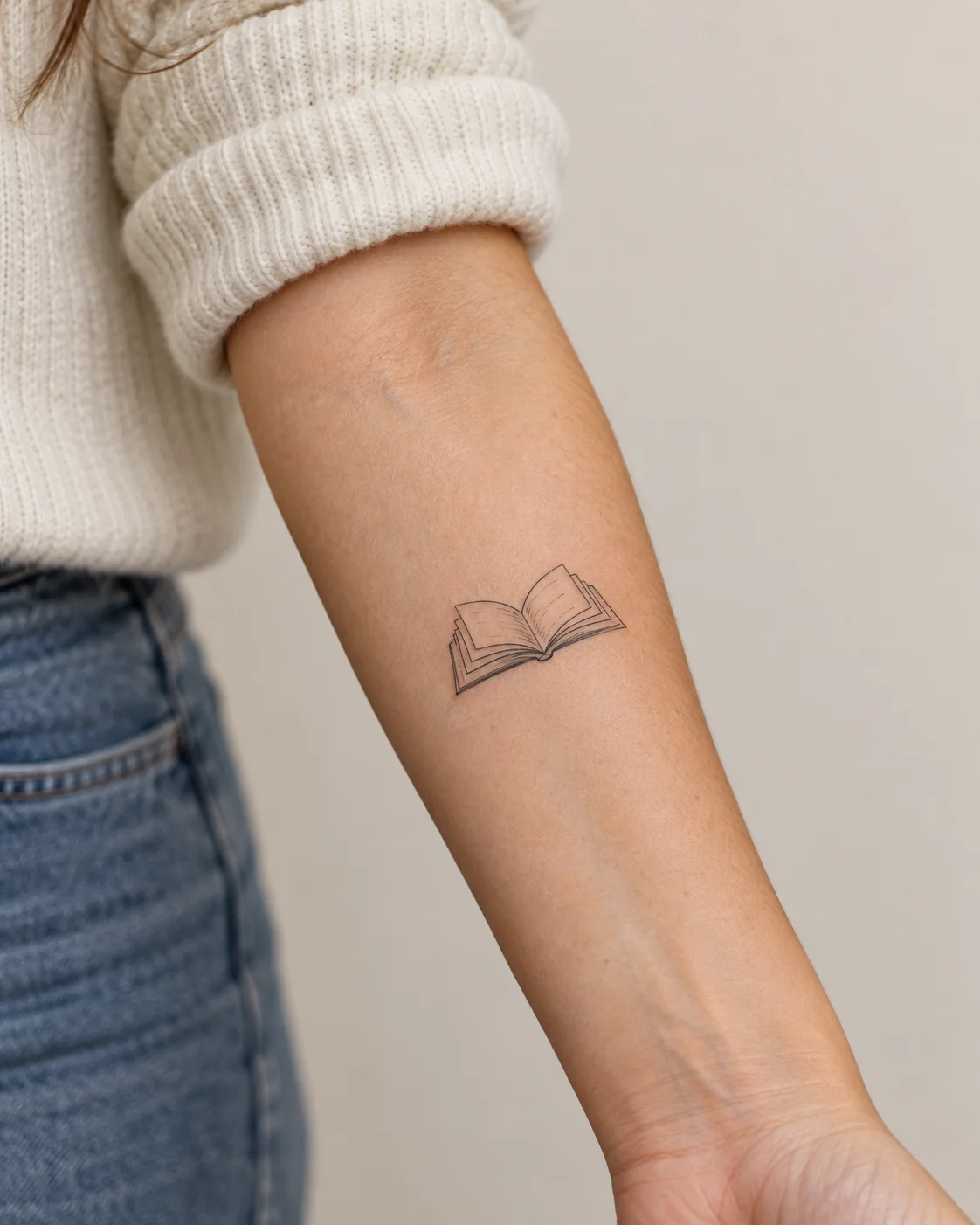 Small Open Book fine line tattoo concept on the inner forearm