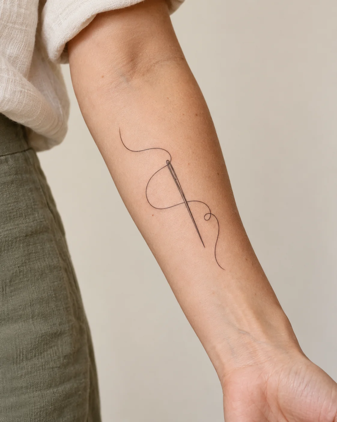 Thread and Needle fine line tattoo concept on the inner forearm
