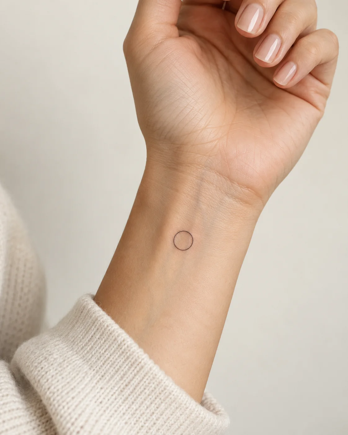 Tiny Open Circle fine line tattoo concept on the inner wrist