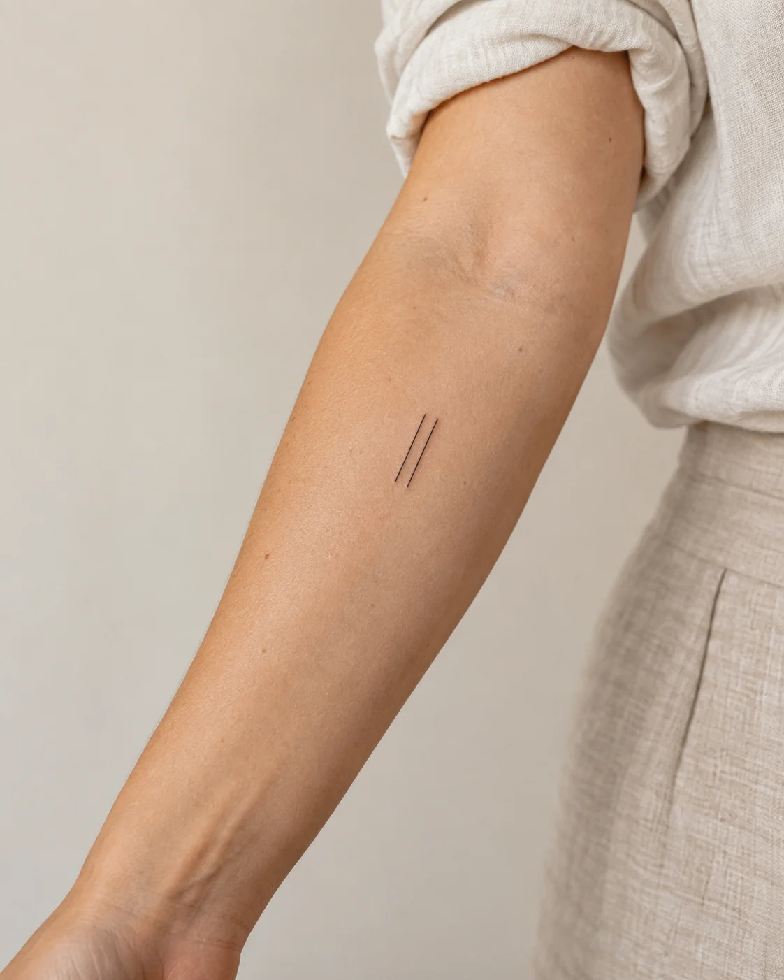 Two Short Parallel Lines fine line tattoo concept on the outer forearm